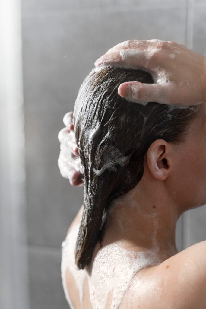 young woman applying anti dandruff product Is L'Oréal Paris Colour Protect Shampoo Really Effective? A Review